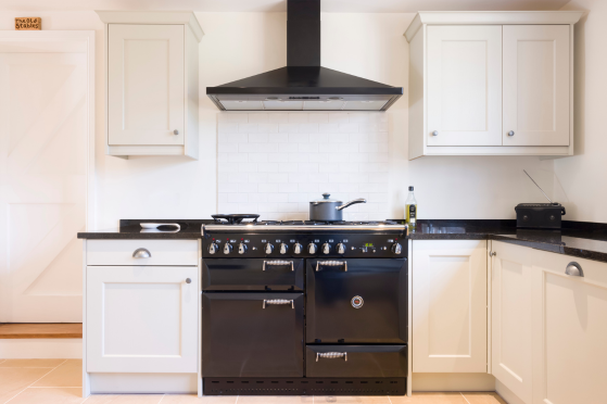 A modern kitchen featuring a black stove and white cabinets